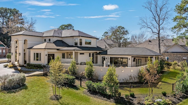 back of house featuring a lawn, fence private yard, and stucco siding