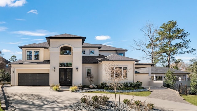 prairie-style house with driveway, a garage, fence, french doors, and stucco siding