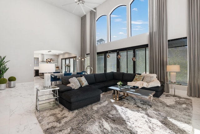 living area featuring arched walkways, marble finish floor, and ceiling fan