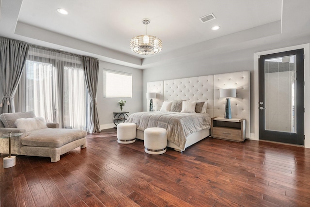 bedroom featuring a tray ceiling, dark wood finished floors, and visible vents