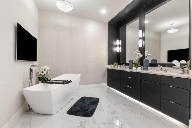 bathroom with double vanity, marble finish floor, a freestanding tub, and a sink