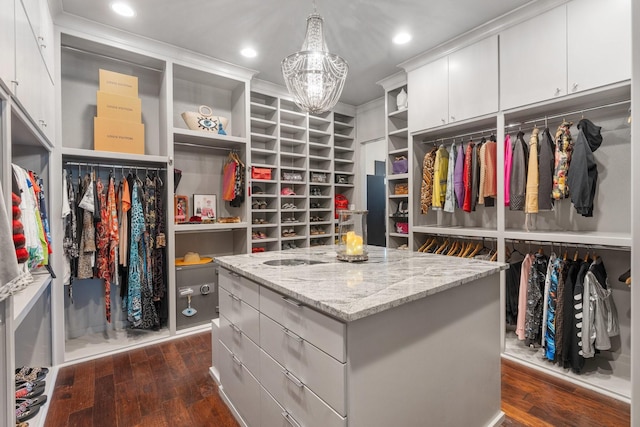 walk in closet with dark wood-style flooring and a notable chandelier