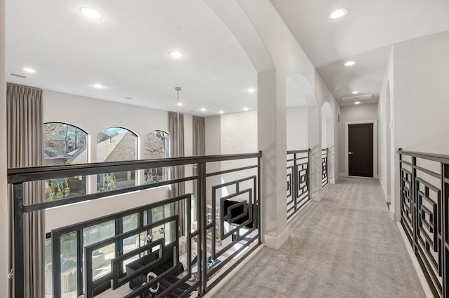 hallway featuring arched walkways, light carpet, visible vents, and recessed lighting