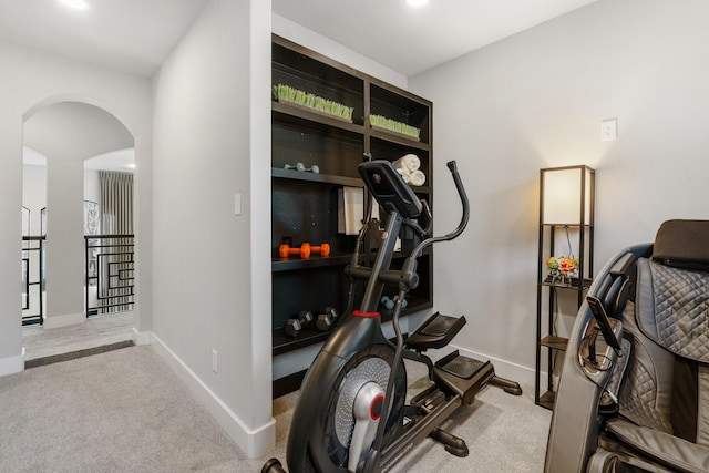 workout room featuring arched walkways, carpet, and baseboards