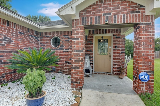 entrance to property featuring brick siding and roof with shingles