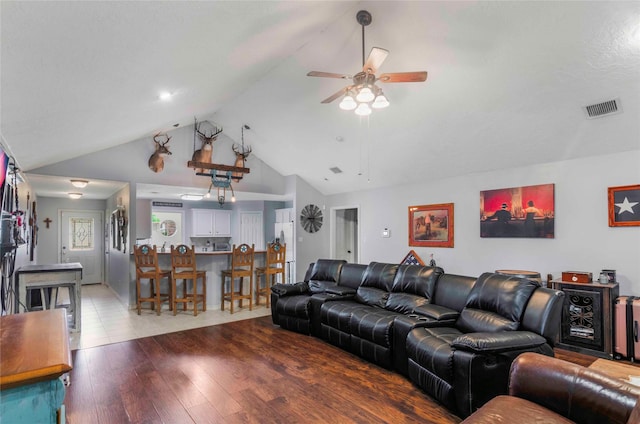 living room featuring ceiling fan, visible vents, vaulted ceiling, and hardwood / wood-style floors