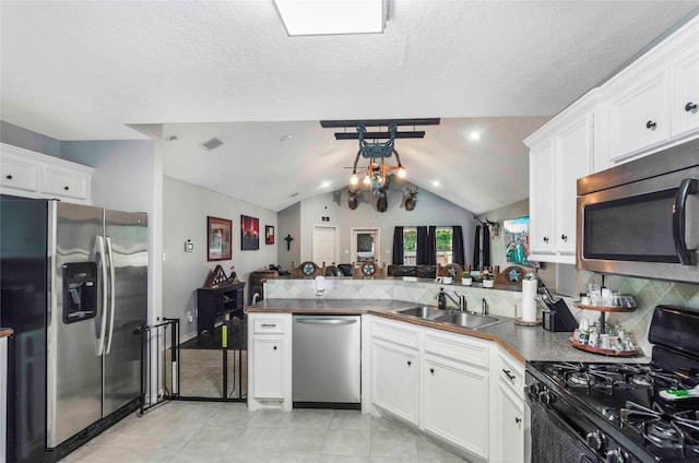 kitchen with visible vents, lofted ceiling, appliances with stainless steel finishes, a peninsula, and a sink