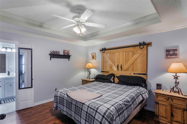 bedroom with baseboards, wood finished floors, a tray ceiling, crown molding, and a sink