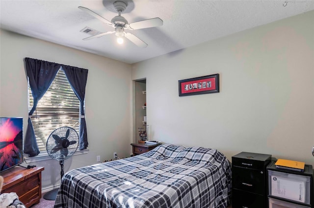 bedroom featuring a textured ceiling, visible vents, and a ceiling fan