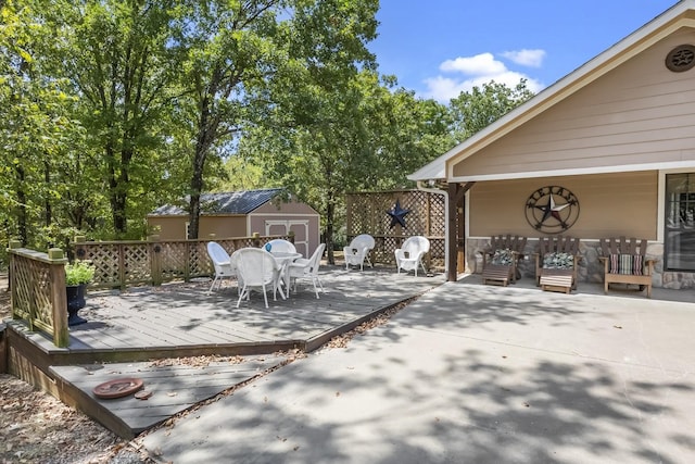 wooden terrace with a storage shed, outdoor dining space, and an outbuilding