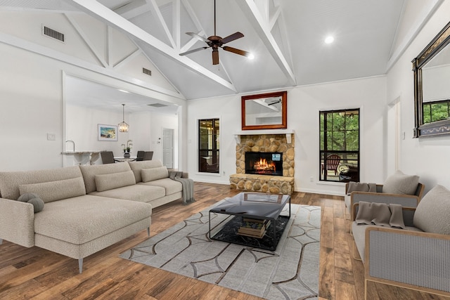 living room with a fireplace, wood-type flooring, visible vents, ceiling fan, and high vaulted ceiling