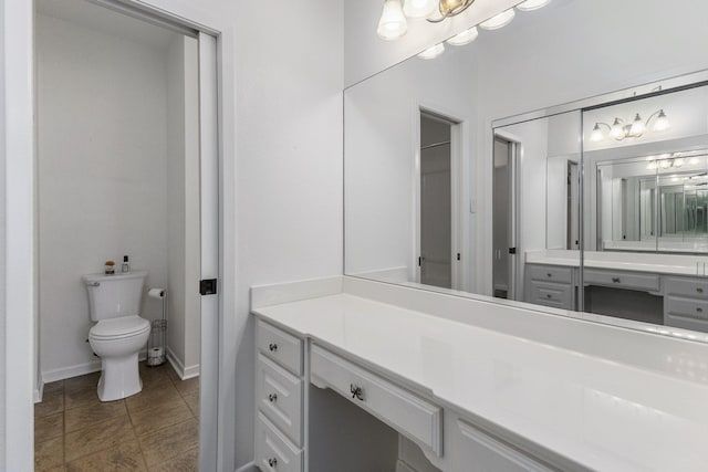 bathroom with baseboards, vanity, toilet, and tile patterned floors