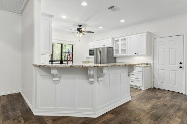 kitchen featuring visible vents, appliances with stainless steel finishes, glass insert cabinets, white cabinets, and a kitchen bar