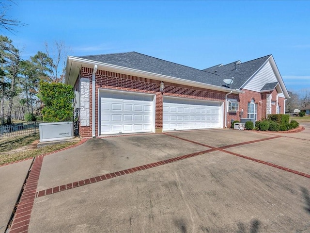 view of side of home with a garage, brick siding, a shingled roof, fence, and driveway