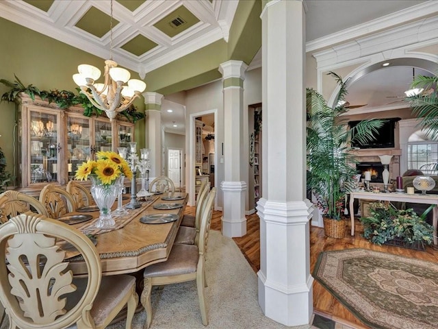 dining room featuring ornamental molding, coffered ceiling, a lit fireplace, and ornate columns