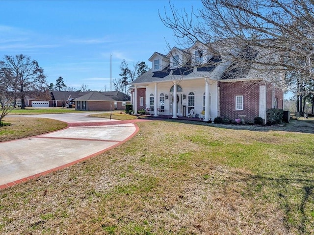 cape cod house with a front yard, covered porch, brick siding, and concrete driveway