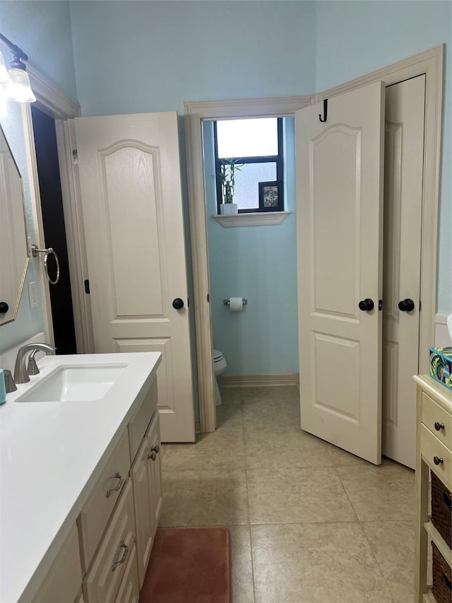 bathroom featuring toilet, tile patterned flooring, baseboards, and vanity