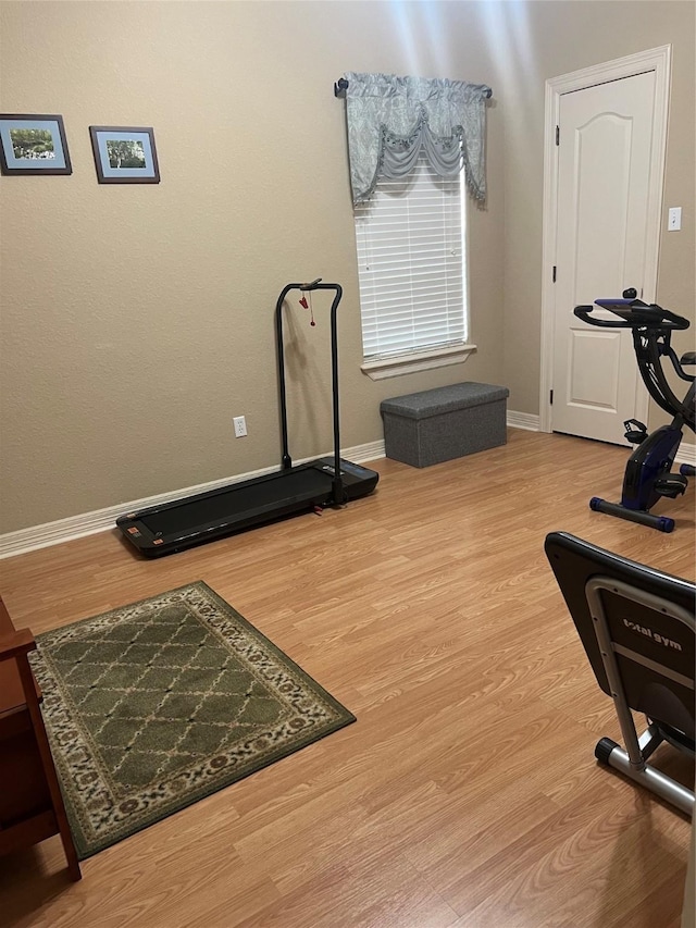 exercise room with wood finished floors and baseboards