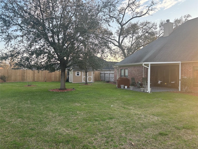 view of yard featuring an outbuilding, a storage unit, a patio area, and a fenced backyard