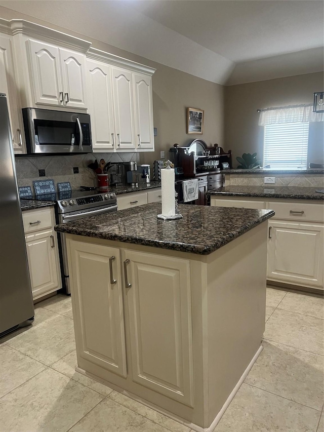 kitchen featuring white cabinets, decorative backsplash, lofted ceiling, a center island, and stainless steel appliances