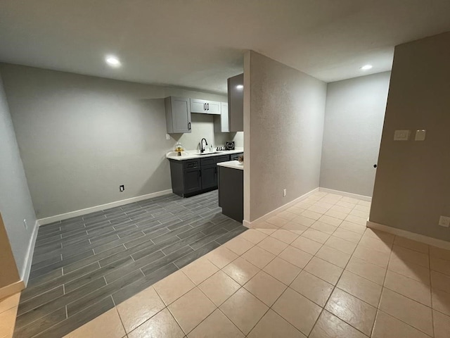 kitchen with recessed lighting, gray cabinets, light countertops, and a sink