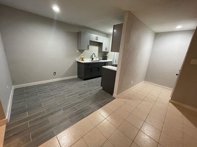 kitchen with baseboards, light countertops, a sink, and recessed lighting