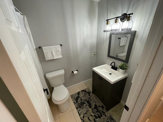 bathroom with toilet, tile patterned flooring, baseboards, and vanity