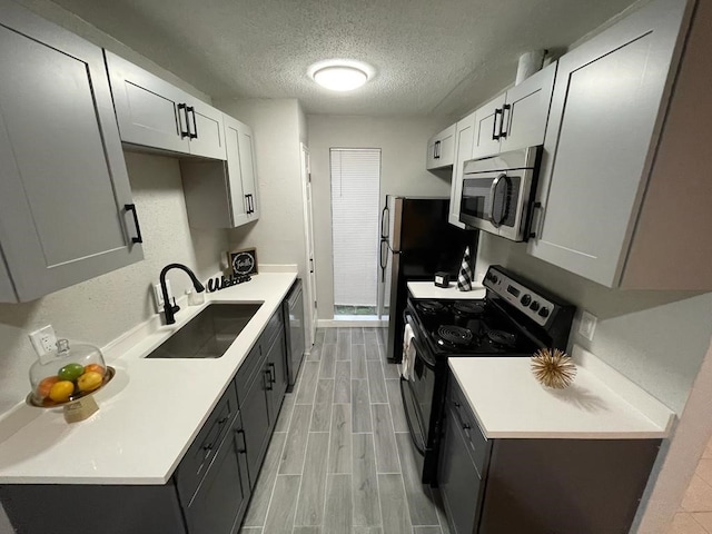 kitchen featuring a sink, stainless steel microwave, light countertops, and electric stove