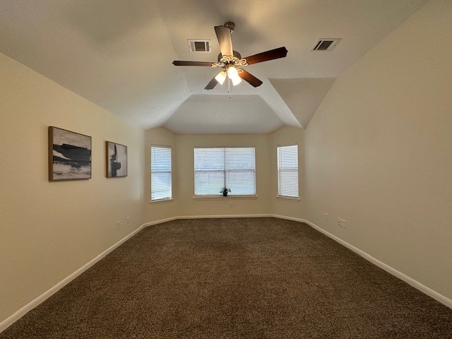 spare room with lofted ceiling, dark carpet, visible vents, and baseboards