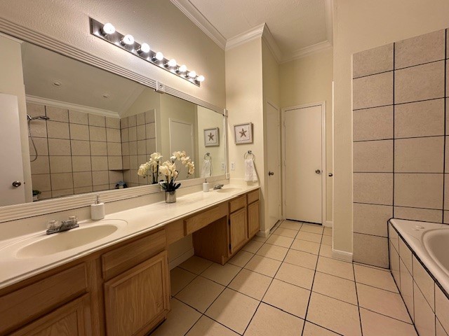 bathroom with a relaxing tiled tub, double vanity, ornamental molding, tile patterned flooring, and a sink