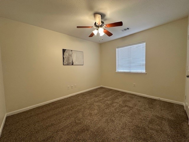 unfurnished room with baseboards, visible vents, and dark colored carpet