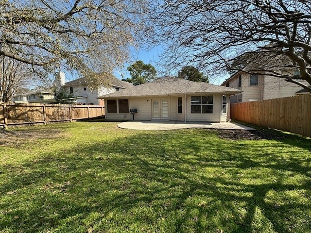 rear view of house with a fenced backyard, french doors, a lawn, and a patio