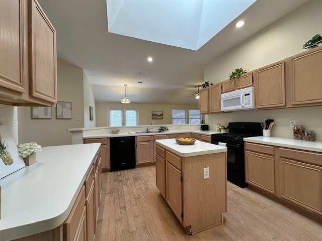 kitchen featuring a peninsula, black appliances, light wood-style flooring, and light countertops