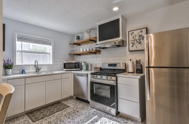 kitchen with stainless steel appliances, light countertops, a sink, and under cabinet range hood