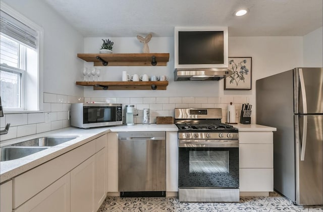 kitchen with tasteful backsplash, light countertops, appliances with stainless steel finishes, white cabinets, and ventilation hood