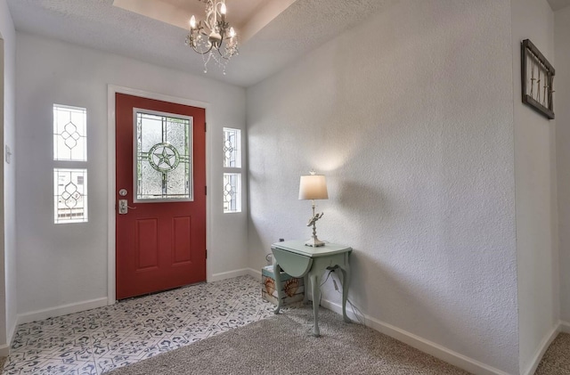 entryway featuring a textured ceiling, baseboards, a notable chandelier, and a textured wall