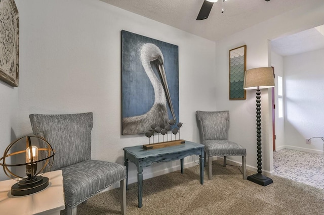 living area with carpet, ceiling fan, a textured ceiling, and baseboards