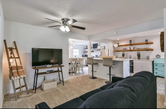 living area featuring a ceiling fan, baseboards, a textured ceiling, and light colored carpet