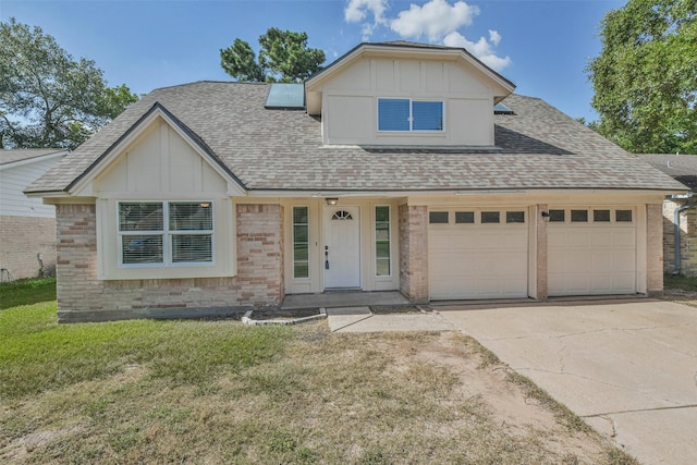 view of front facade featuring brick siding, a shingled roof, concrete driveway, board and batten siding, and a front yard