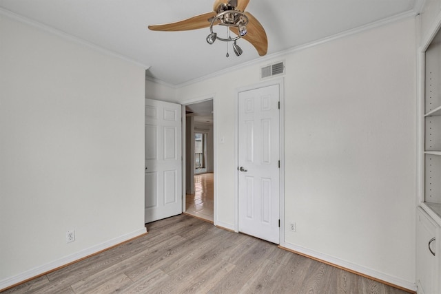 unfurnished bedroom with visible vents, light wood-style floors, ornamental molding, ceiling fan, and baseboards