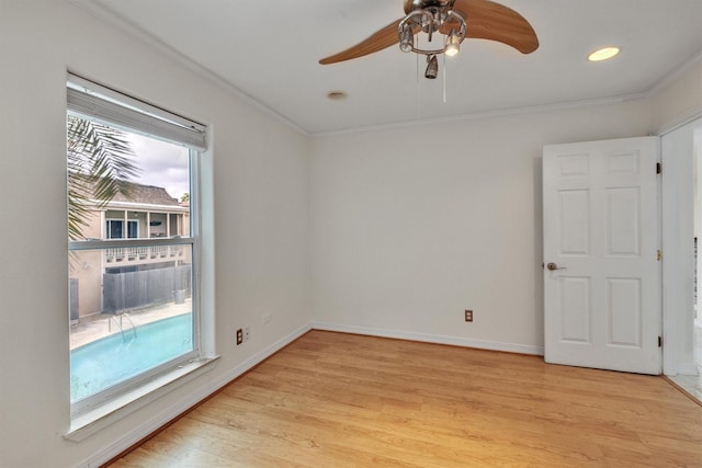 spare room with light wood-style floors, crown molding, baseboards, and ceiling fan