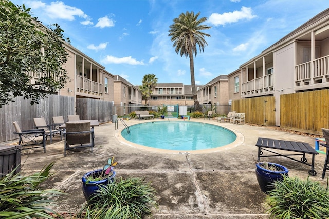 community pool with a residential view, fence, and a patio