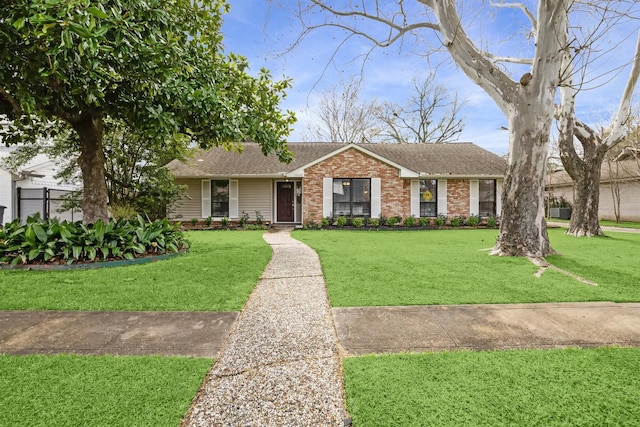 ranch-style home featuring a front lawn, a shingled roof, and brick siding