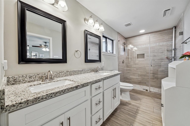 bathroom featuring toilet, a stall shower, visible vents, and a sink