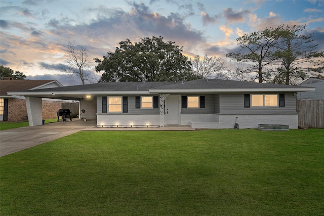 ranch-style home with an attached carport, brick siding, driveway, and a lawn