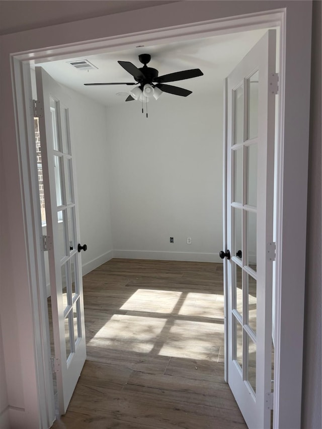 spare room featuring baseboards, visible vents, wood finished floors, and french doors