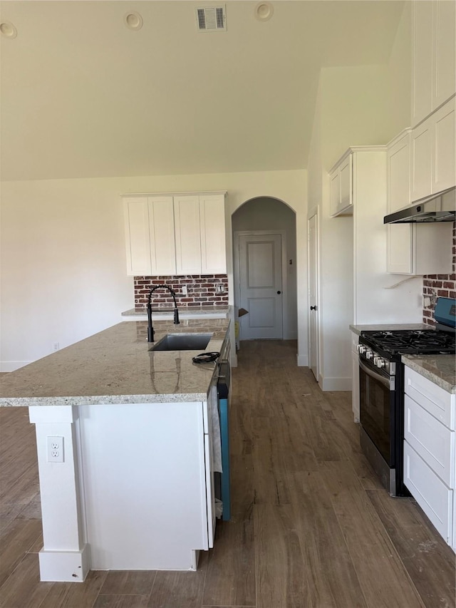 kitchen with tasteful backsplash, visible vents, light stone counters, stainless steel range with gas cooktop, and a sink