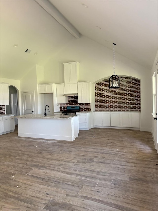 kitchen with stainless steel range, arched walkways, white cabinets, and wood finished floors