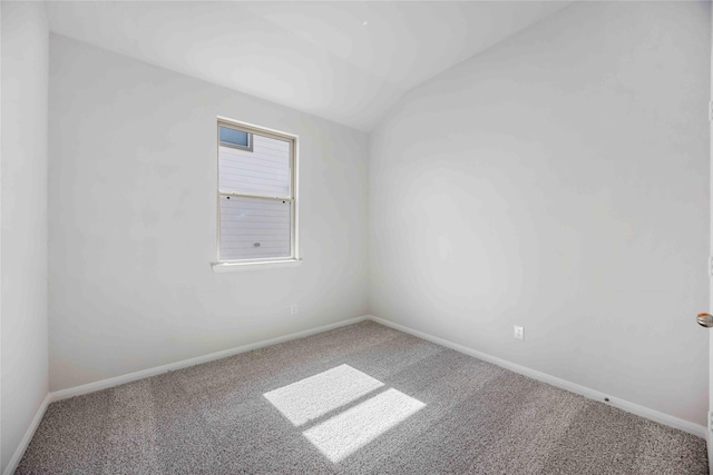 spare room featuring vaulted ceiling, carpet, and baseboards