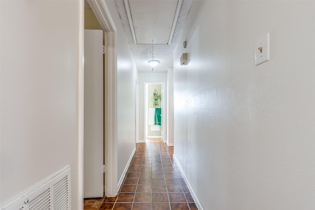 hallway featuring attic access, visible vents, and baseboards